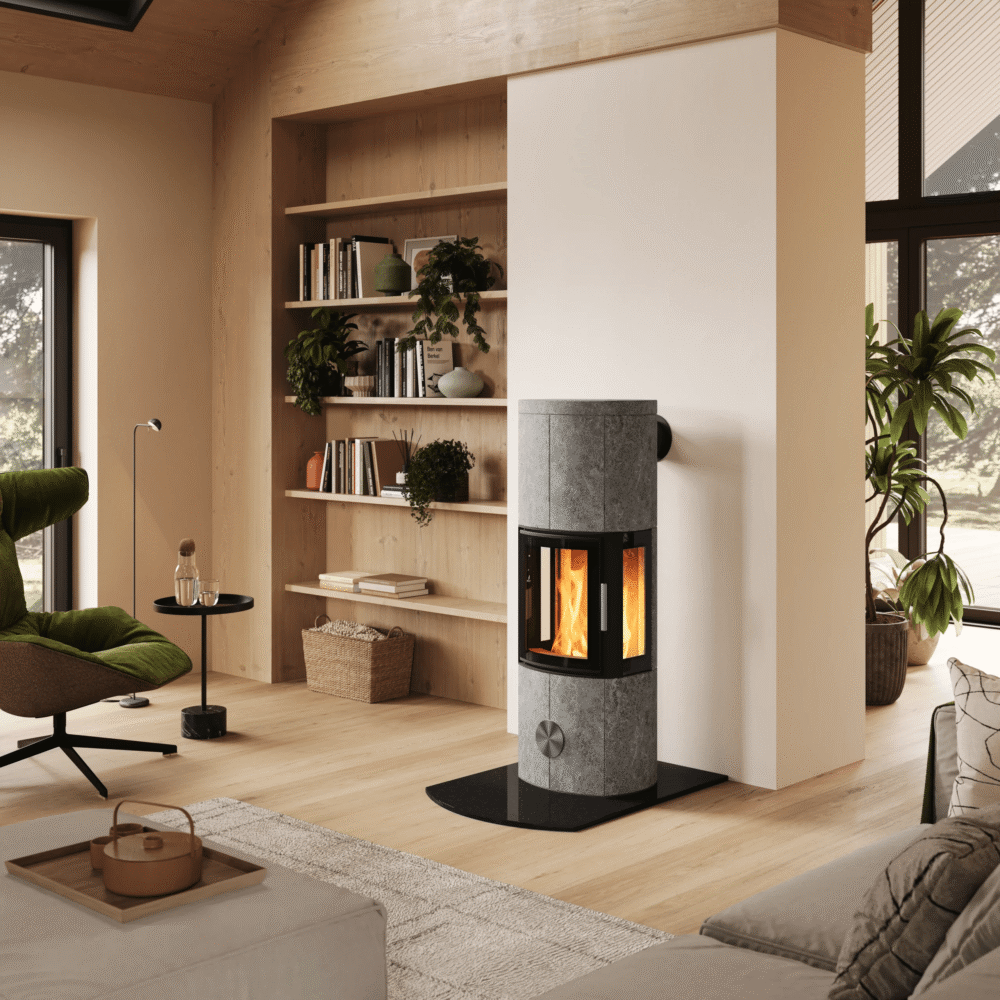 Un poêle de masse moderne placé au centre d'un intérieur scandinave lumineux, avec un escalier en bois, un coin salon et un service à café au premier plan.