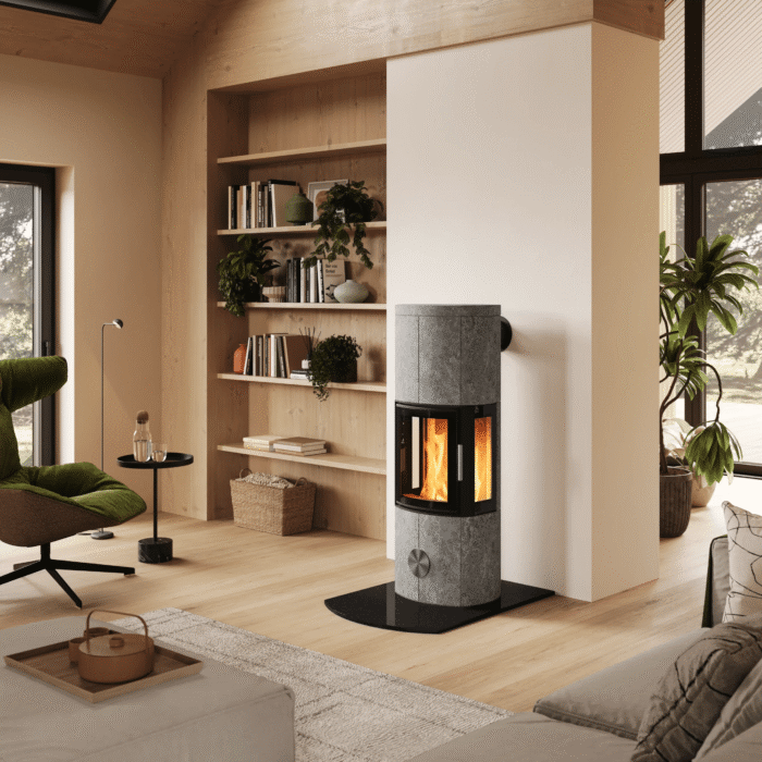 Un poêle de masse moderne placé au centre d'un intérieur scandinave lumineux, avec un escalier en bois, un coin salon et un service à café au premier plan.